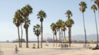 Kaliforniya plaj estetiği, insanlar bisiklet yolunda bisiklet sürüyor. Bulanık, odaklanmış arka plan. Santa Monica Amerikan Pasifik Okyanusu Tatil Köyü, Los Angeles CA ABD 'deki iskele ve palmiyelerdeki eğlence parkı.