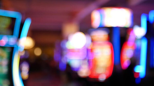 Defocused slot machines glow in casino on fabulous Las Vegas Strip, USA. Blurred gambling jackpot slots in hotel near Fremont street. Illuminated neon fruit machine for risk money playing and betting.