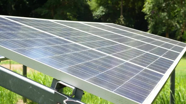 Solar panels over grass on sunny day. Row of alternative power plants on lawn producing ecological energy. Conservation of the environment and go green concept. Modern technologies and innovations