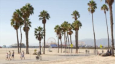 Kaliforniya plaj estetiği, insanlar bisiklet yolunda bisiklet sürüyor. Bulanık, odaklanmış arka plan. Santa Monica Amerikan Pasifik Okyanusu Tatil Köyü, Los Angeles CA ABD 'deki iskele ve palmiyelerdeki eğlence parkı.