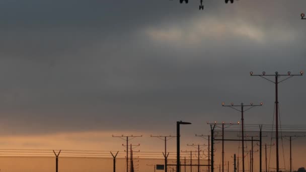 Vliegtuig landing in LAX luchthaven bij zonsondergang, Los Angeles, Californië, Verenigde Staten. Passagiersvlucht of vrachtvliegtuig silhouet, dramatische wolkendek. Vliegtuigen arriveren op het vliegveld. Internationaal vliegverkeer — Stockvideo