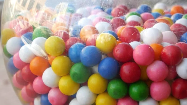 Colorful gumballs in classic vending machine, USA. Multi colored buble gums, coin operated retro dispenser. Chewing gum candies as symbol of childhood and summertime. Mixed sweets in vintage automate.