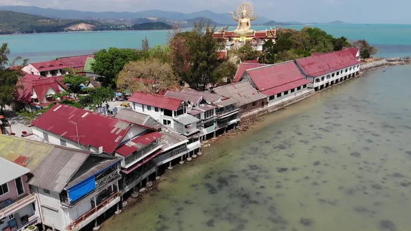 Island with Buddhist temple and many houses. Aerial view of island with Buddhist temple with statue Big Buddha surrounded by traditional houses on stilts in bay of Pacific ocean on Samui, Thailand — Stock Image Island Buddhist Temple Many Houses Aerial View Island Buddhist Temple Royalty Free Stock Images
