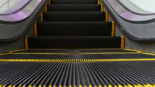 Vista en bucle de ángulo bajo de escaleras mecánicas modernas. Mecanismo de ascensor automatizado. Línea amarilla en escalera iluminada con luz púrpura. Escalera de maquinaria vacía futurista moviéndose recta — Vídeo de stock