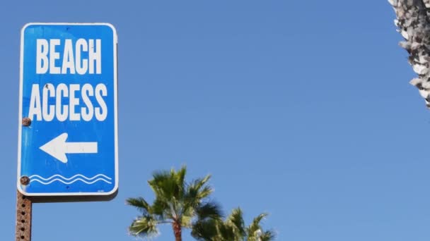 Beach sign and palms in sunny California, USA. Palm trees and seaside signpost. Oceanside pacific tourist resort aesthetic. Symbol of travel holidays and summertime vacations. Beachfront promenade — Stock Video