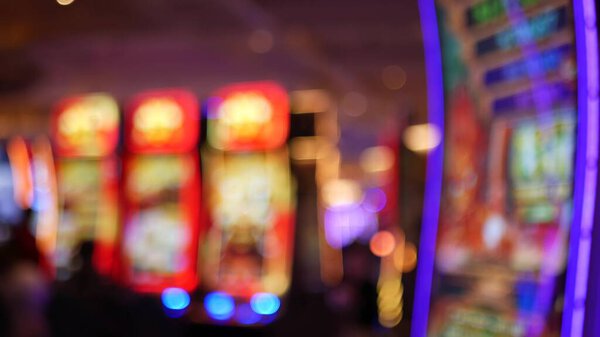 Defocused slot machines glow in casino on fabulous Las Vegas Strip, USA. Blurred gambling jackpot slots in hotel near Fremont street. Illuminated neon fruit machine for risk money playing and betting.