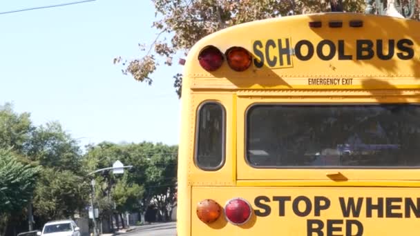 Gele iconische schoolbus in Los Angeles, Californië, USA. Klassieke truck voor studenten backview. Stoplichten voor de veiligheid van het vervoer van kinderen. Openbaar personenvervoer voor kinderen in een buitenwijk — Stockvideo