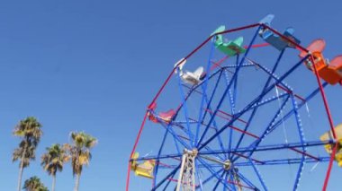 Klasik canlı yaz mevsimi, eğlence ve çocukluk sembolü, yeşil tropik palmiye yaprakları. İkonik renkli dönme dolap cazibesi. Newport, California Pasifik Okyanusu sahil beldesi Los Angeles ABD yakınları.