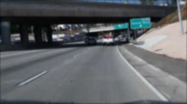Los Angeles, Kaliforniya 'da şehirlerarası otobanda araba sürüyorum. Yoğun otoyoldaki arabanın cam ön camından odaklanmış görüntüsü. Bulanık banliyö yolu. Kamera Los Angeles 'ta.