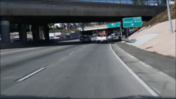 Los Angeles, Kaliforniya 'da şehirlerarası otobanda araba sürüyorum. Yoğun otoyoldaki arabanın cam ön camından odaklanmış görüntüsü. Bulanık banliyö yolu. Kamera Los Angeles 'ta. — Stok video