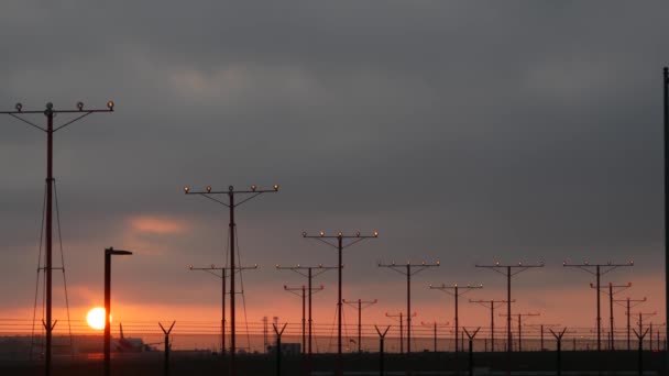 ロサンゼルス、カリフォルニア州の日没時にLAX空港に飛行機の着陸。旅客便や貨物飛行機のシルエット、劇的な雲。飛行場への航空機到着。国際輸送機 — ストック動画