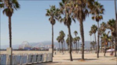 Kaliforniya plaj estetiği, insanlar bisiklet yolunda bisiklet sürüyor. Bulanık, odaklanmış arka plan. Santa Monica Amerikan Pasifik Okyanusu Tatil Köyü, Los Angeles CA ABD 'deki iskele ve palmiyelerdeki eğlence parkı.