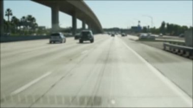 Los Angeles, Kaliforniya 'da şehirlerarası otobanda araba sürüyorum. Yoğun otoyoldaki arabanın cam ön camından odaklanmış görüntüsü. Bulanık banliyö yolu. Kamera Los Angeles 'ta.