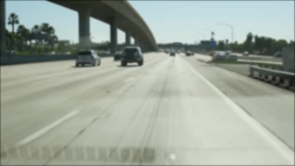 Подорожуючи міжміською автострадою в Лос-Анджелесі, штат Каліфорнія, США. Розбитий вигляд з вітрового скла автомобіля на інтерстейті. Розмите передмістя багатосмугове шосе. Камера всередині автомашини в Лос - Анджелесі. — стокове відео