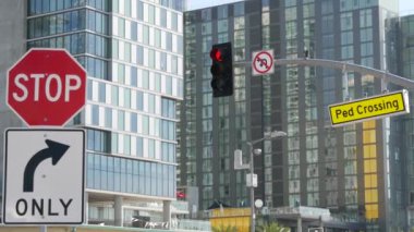 Trafik ışığı ve uyarı işareti, ABD 'de yol kavşağı. Ulaşım güvenliği, kurallar ve yönetmelikler sembolü. Modern şehir manzarasına karşı garaj yolu geçiş sinyali, San Diego, California