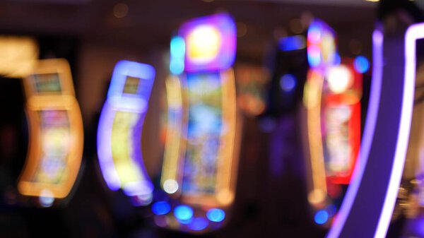 Defocused slot machines glow in casino on fabulous Las Vegas Strip, USA. Blurred gambling jackpot slots in hotel near Fremont street. Illuminated neon fruit machine for risk money playing and betting.