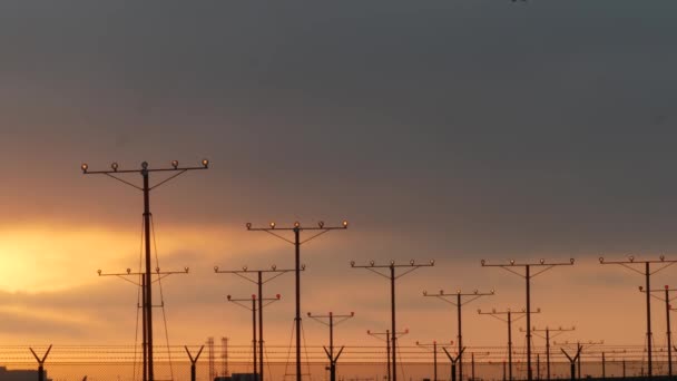 Avion atterrissant à l'aéroport au coucher du soleil, Los Angeles, Californie États-Unis. Vol passager ou silhouette d'avion cargo, paysage nuageux spectaculaire. Arrivée de l'avion à l'aérodrome. Transport international volant — Video