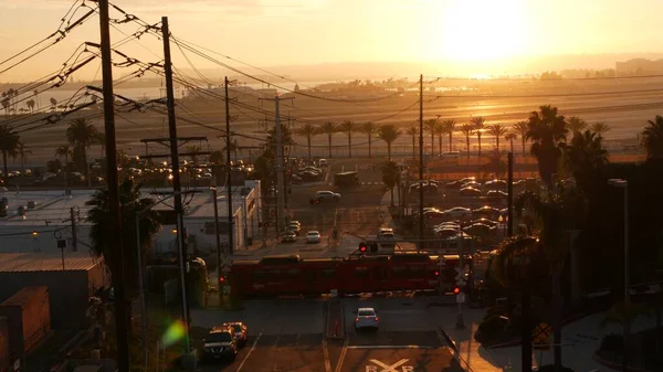 SAN DIEGO, CALIFORNIA USA - 15 HAZİRAN 2020: Uluslararası Lindbergh havaalanı yakınlarından geçiş. Gün batımında demiryolu kırmızı tramvay ve pist. MTS Tramvay taşımacılığı, arabalar ve demiryolu taşımacılığı.