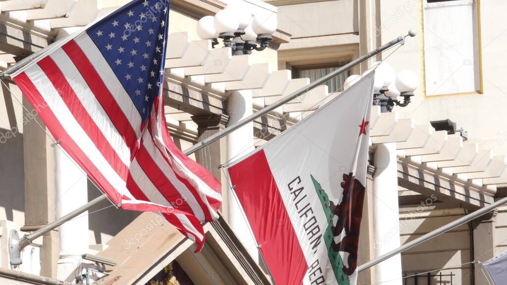 Flags of California and United States waving on flagpole in Gaslamp, center quarter of San Diego. Bear emblem of Republic and Star-Spangled Banner on flagstaff. Symbol of ptriotism and government.