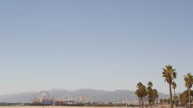 Kaliforniya plaj estetiği, klasik dönme dolap, Santa Monica Pasifik Okyanusu 'ndaki iskeledeki eğlence parkı. Yaz ikonik manzarası, palmiye ağaçları ve gökyüzü, kopya alanı ile Los Angeles 'ın sembolü, CA USA