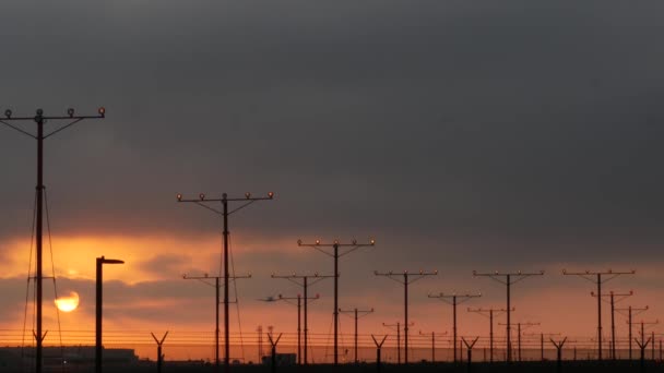 Avión aterrizando en el aeropuerto LAX al atardecer, Los Ángeles, California, EE.UU. Vuelo de pasajeros o silueta de avión de carga, paisaje nublado dramático. Llegada de aviones al aeródromo. Transporte internacional volando — Vídeo de stock