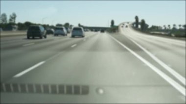 Los Angeles, Kaliforniya 'da şehirlerarası otobanda araba sürüyorum. Yoğun otoyoldaki arabanın cam ön camından odaklanmış görüntüsü. Bulanık banliyö yolu. Kamera Los Angeles 'ta.
