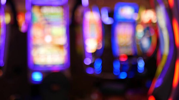 Defocused slot machines glow in casino on fabulous Las Vegas Strip, USA. Blurred gambling jackpot slots in hotel near Fremont street. Illuminated neon fruit machine for risk money playing and betting.