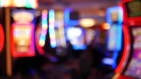 Defocused slot machines glow in casino on fabulous Las Vegas Strip, USA. Blurred gambling jackpot slots in hotel near Fremont street. Illuminated neon fruit machine for risk money playing and betting.