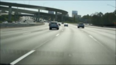 Los Angeles, Kaliforniya 'da şehirlerarası otobanda araba sürüyorum. Yoğun otoyoldaki arabanın cam ön camından odaklanmış görüntüsü. Bulanık banliyö yolu. Kamera Los Angeles 'ta.