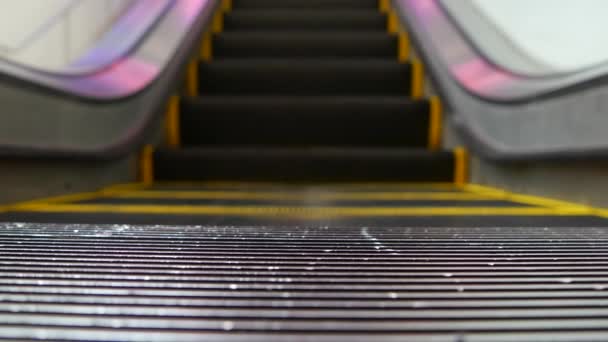 Vista en bucle de ángulo bajo de escaleras mecánicas modernas. Mecanismo de ascensor automatizado. Línea amarilla en escalera iluminada con luz púrpura. Escalera de maquinaria vacía futurista moviéndose recta — Vídeos de Stock