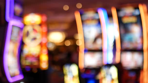 Defocused slot machines glow in casino on fabulous Las Vegas Strip, USA. Blurred gambling jackpot slots in hotel near Fremont street. Illuminated neon fruit machine for risk money playing and betting — Stock Video