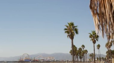 Kaliforniya plaj estetiği, klasik dönme dolap, Santa Monica Pasifik Okyanusu 'ndaki iskeledeki eğlence parkı. Yaz ikonik manzarası, palmiye ağaçları ve gökyüzü, kopya alanı ile Los Angeles 'ın sembolü, CA USA