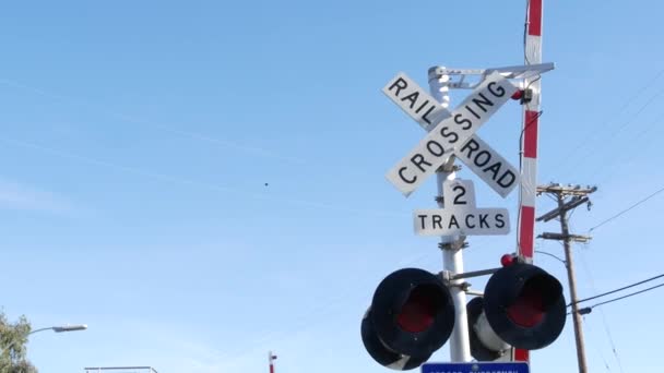 Señal de advertencia de cruce de nivel en EE.UU. Aviso cruzado y semáforo rojo en la intersección de carreteras ferroviarias en California. Transporte ferroviario símbolo de seguridad. Señal de precaución sobre el peligro y la vía del tren — Vídeos de Stock