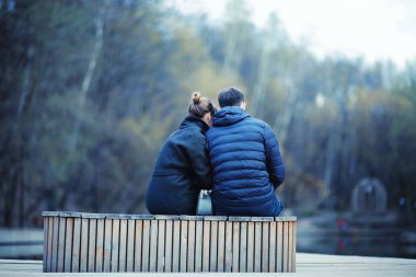 Genç erkek ve kadın kış Park, romantik mutlu çift birlikte bankta oturan