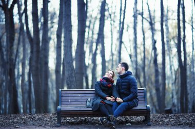 Genç erkek ve kadın kış Park, romantik mutlu çift birlikte bankta oturan