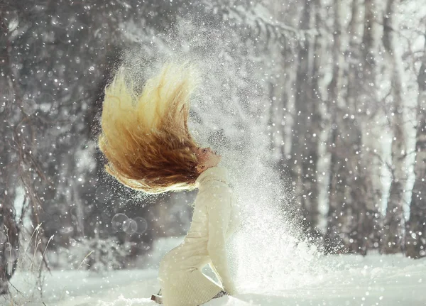 beautiful blonde woman with flying hair in snowy winter forest