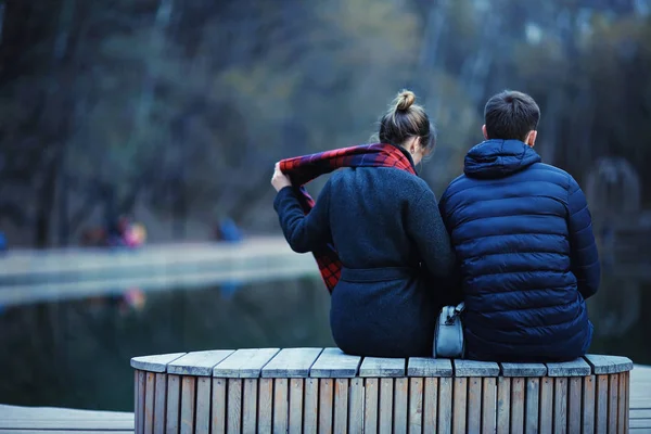 年轻的男人和女人坐在板凳上在冬季公园 浪漫愉快的情侣 — 图库照片