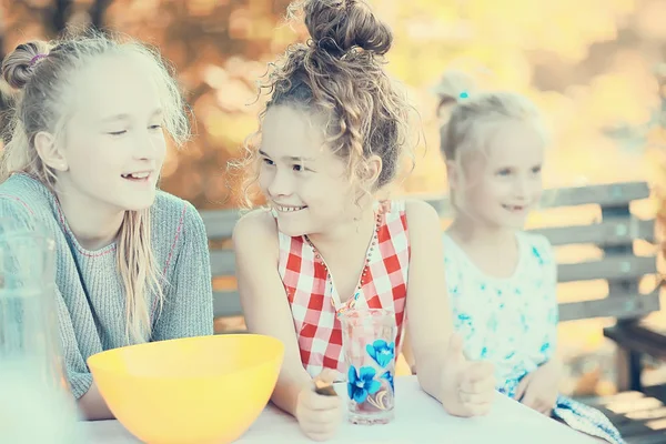 三个快乐的小女孩在夏天的花园里坐在长凳上的乐趣 — 图库照片