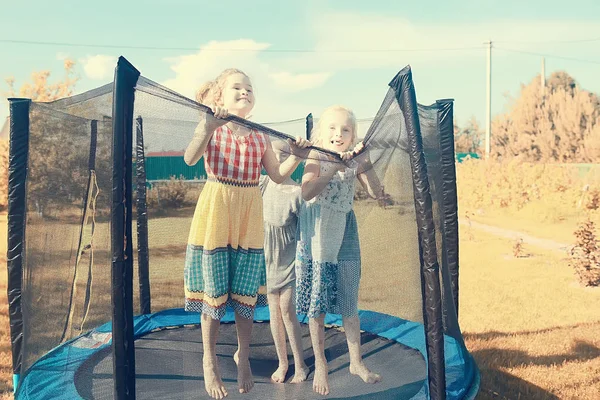 三个小女孩姐妹在夏天在户外的蹦床上跳来跳去 — 图库照片