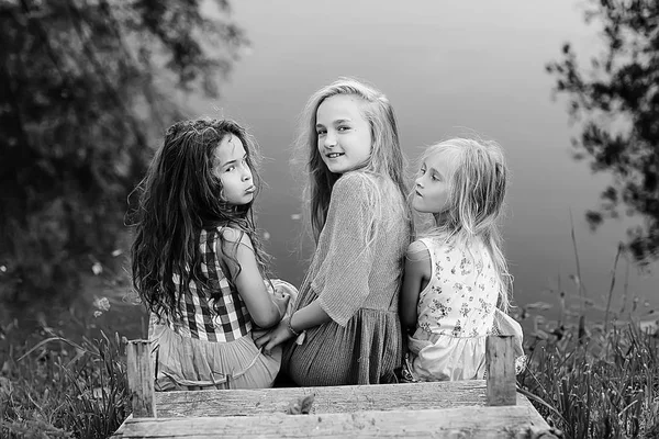 三可爱的小女孩在河岸上 愉快的女朋友在度假 姐妹在河上 幸福和家庭 — 图库照片
