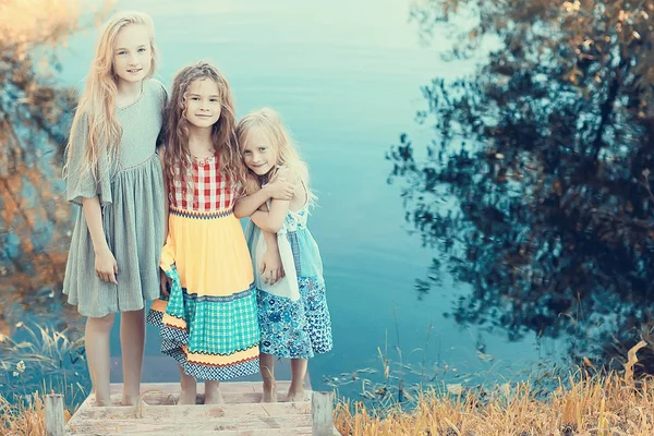 三可爱的小女孩在河岸上 愉快的女朋友在度假 姐妹在河上 幸福和家庭 — 图库照片