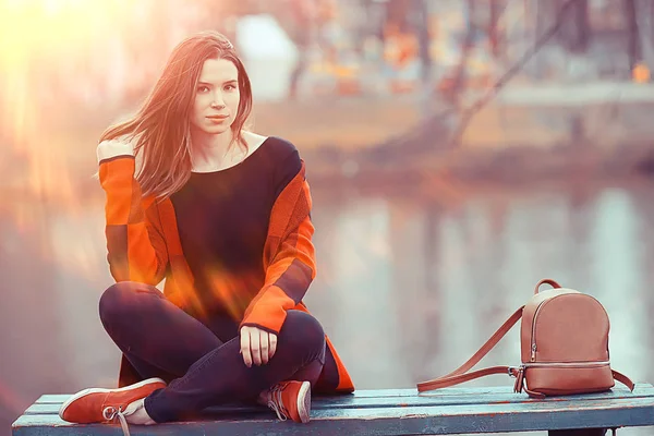 湖の秋の風景のベンチに座ってリラックスした若いブルネットの女性 — ストック写真
