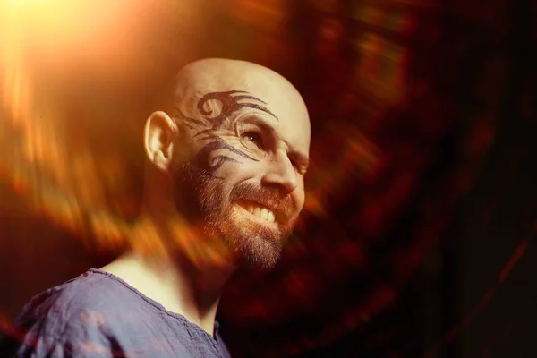 portrait of brutal bearded man with tattoo on face