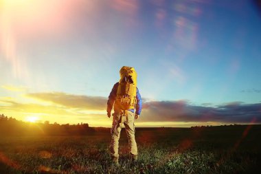 gün batımı, zam, Aktif istirahat kavramı, yeşil çim üzerinde sırt çantası ile acımasız adam