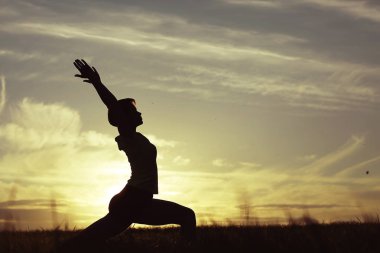 Gün batımında yoga yaz Lawn yaparken genç kadın silüeti 