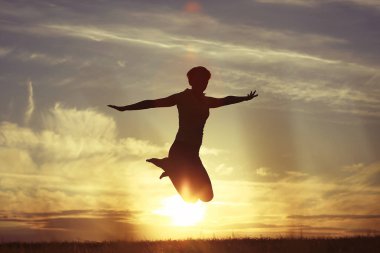 Günbatımı gökyüzü, mutluluk kavramı karşı açık atlama genç kadın silüeti