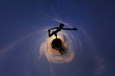 Renkli gökyüzü günbatımı, uyum kavramı karşı küçük gezegen üzerinde duran yoga yaparken genç kadın silüeti