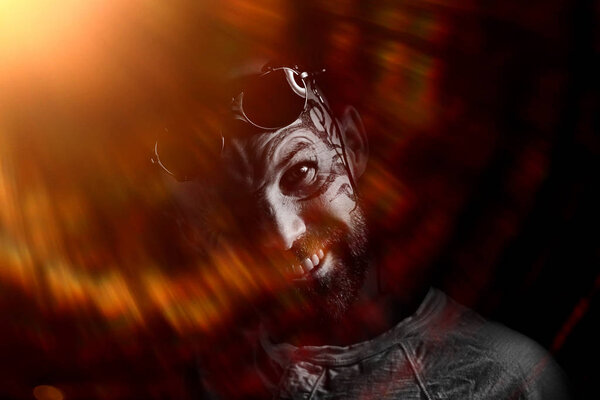 портрет жестокого бородатого мужчины с татуировкой на лице
