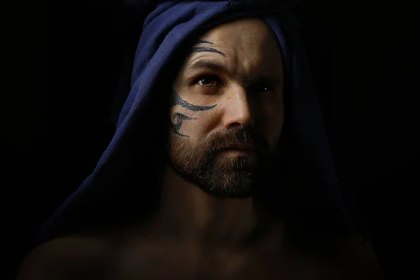 portrait of brutal bearded man with tattoo on face