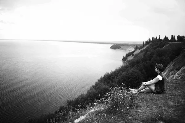 川の土手に座っている孤独な若い美しい若い女性の肖像画 — ストック写真